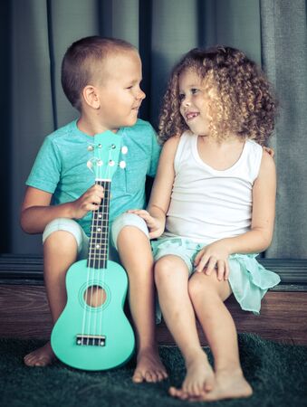 Portrait of a cute kids sitting ouddoor with ukuleleの写真素材