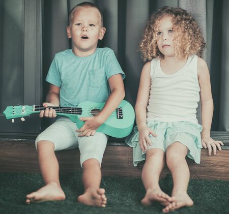 Portrait of a cute kids sitting ouddoor with ukuleleの写真素材