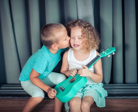 Portrait of a cute kids sitting ouddoor with ukuleleの写真素材