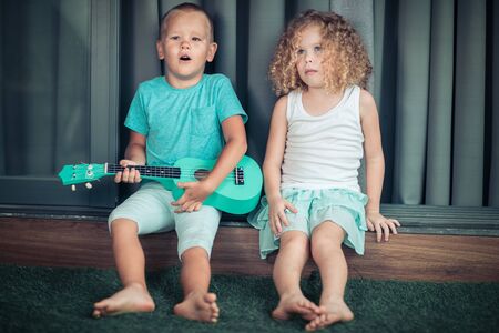 Portrait of a cute kids sitting ouddoor with ukuleleの写真素材