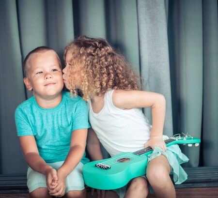 Portrait of a cute kids sitting ouddoor with ukuleleの写真素材