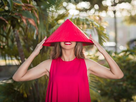 Fashion portrait of a beautiful woman in red conical hat outdoorの写真素材