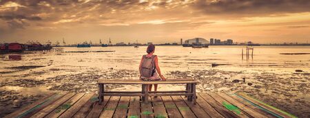 Tourist with backpack at Yeoh jetty at sunrise, Georgetown, Penang, Malaysia. Panorama