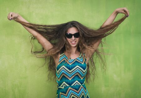 Outdoor portrait of a beautiful woman next green wallの写真素材