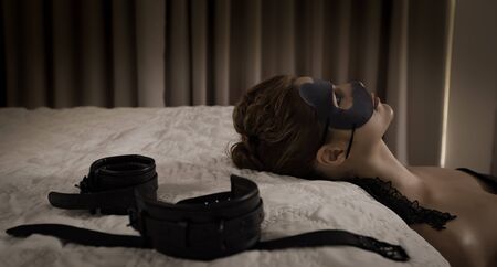 Low key portrait of beautiful submissive woman in handcuffsの写真素材