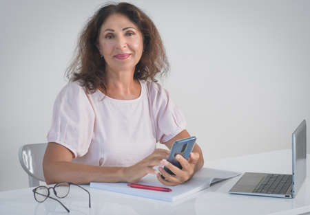 Indoor portrait of a beautiful smiling senior woman working at homeの写真素材