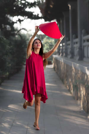 Fashion portrait of a beautiful woman in red conical hat outdoorの写真素材