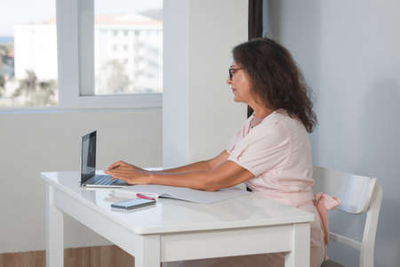 Indoor portrait of a beautiful smiling senior woman working at homeの写真素材