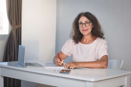 Indoor portrait of a beautiful smiling senior woman working at homeの写真素材