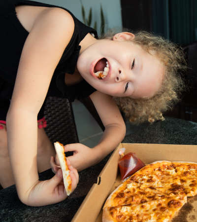 Funny kids eating pizza at homeの写真素材