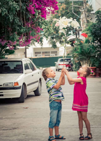 Kids walking by the street with flowerの写真素材