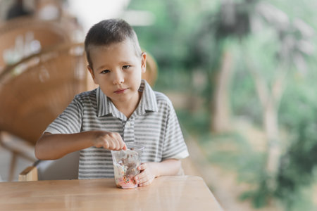 Cute boy eating ice-cream in outdoor cafeの写真素材