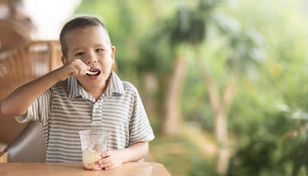 Cute boy eating ice-cream in outdoor cafeの写真素材