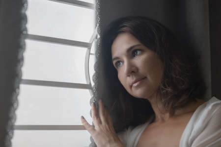 Beautiful woman next to the window. Lockdown concept. Shallow depth of focusの写真素材