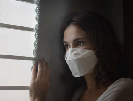 Beautiful woman next to the window. Lockdown concept. Shallow depth of focusの写真素材
