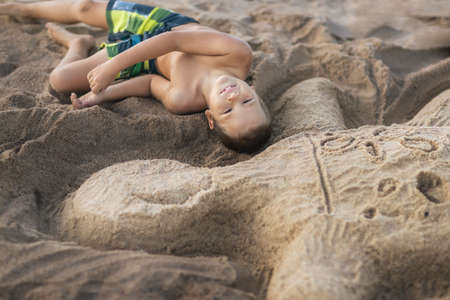 Outdoor portrait of a little cute boy with turtle made from sandの写真素材