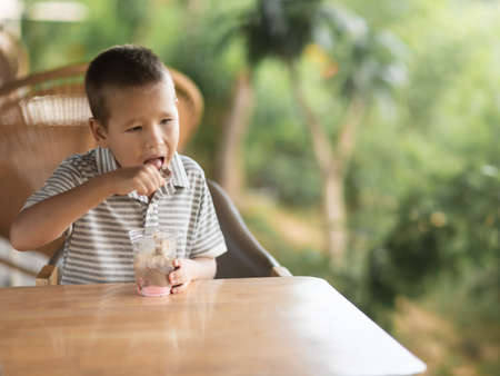 Cute boy eating ice-cream in outdoor cafeの写真素材
