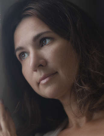 Beautiful woman next to the window. Lockdown concept. Shallow depth of focusの写真素材