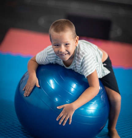 boy doing exercises with ball indoorの写真素材