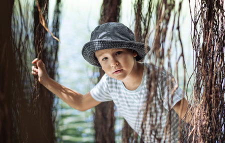 Boy having fun on the lake with banyan treeの写真素材