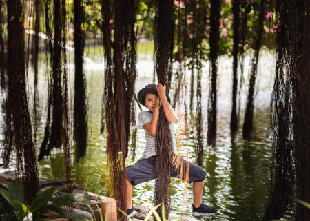 Boy having fun on the lake with banyan treeの写真素材