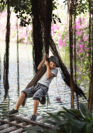 Boy having fun on the lake with banyan treeの写真素材