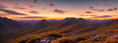 Rugged beauty of a mountain range at golden hour, with the sun setting in the background painting the sky in hues of orange and pinkの素材