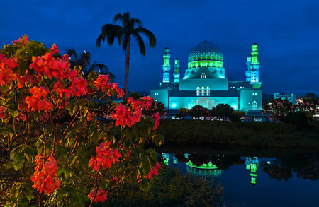 Evening view of Masjid Bandaraya Kota Kinabalu, a famous landmark and tourist attraction in Borneo, glowing at dusk with water reflection and flowers.の写真素材