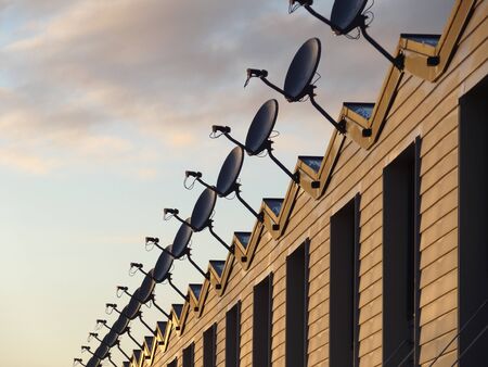 Row of cable television receiving dishes on rooftopの写真素材