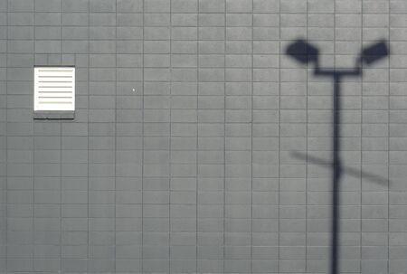Gray brick wall with lamp post shadow compositionの写真素材