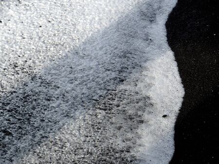 White foam on black sand volcanic beach, Napier New Zealandの写真素材
