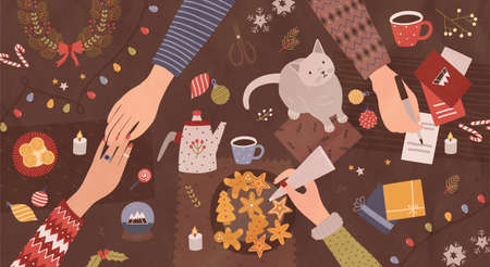 Hands of people sitting around table and preparing for Christmas - making festive decorations, writing on greeting cards, decorating cookies. Top view. Colorful cartoon holiday vector illustration.のイラスト素材