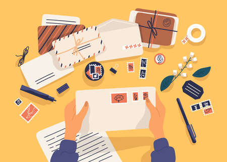 Hands holding envelope with stamps surrounded by papers, postcards, pen on yellow background. Top view. Postcrossing, sending letters through postal service. Flat cartoon vector illustration.のイラスト素材