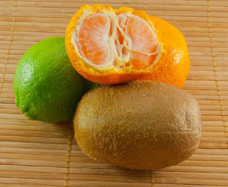 Lime, mandarin, kiwi on a bamboo mat classic colorsの写真素材