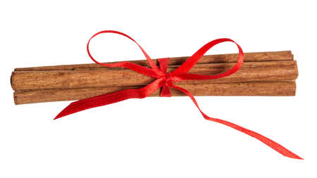 sticks of cinnamon with ribbon bow isolated on whiteの写真素材