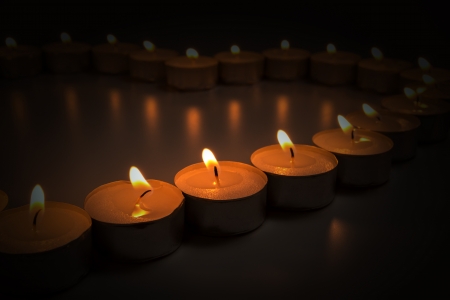 dark composition from rows of burning candlesの写真素材