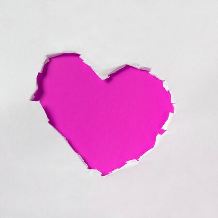 hole in shape of a heart, white and red paperの写真素材