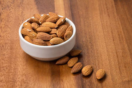 roasted almonds in white porcelain bowl, food background