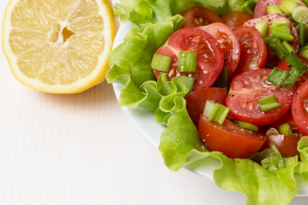 fresh light salad with cherry tomatoes and chives, on white wood tableの写真素材