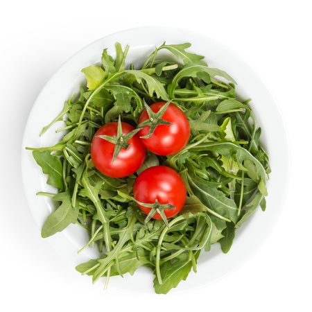 fresh rucola leaves in a bowl with tomatoes, isolated on whiteの写真素材
