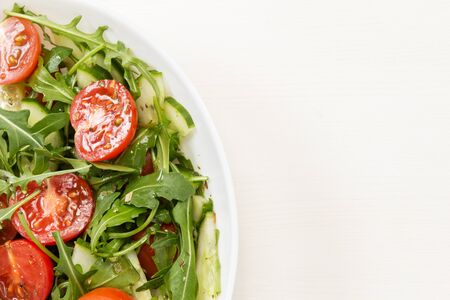 salad from ruccola, cherry tomatoes and cucumber, on wood tableの写真素材