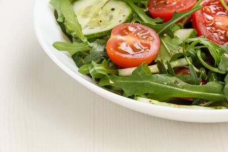 salad from ruccola, cherry tomatoes and cucumber, on wood tableの写真素材