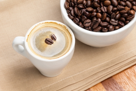 espresso in a cup and cup full of beans on burlap surfaceの写真素材
