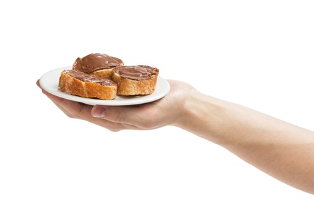 baguette slices spread with nut-choco paste in man hand, isolated on whiteの写真素材