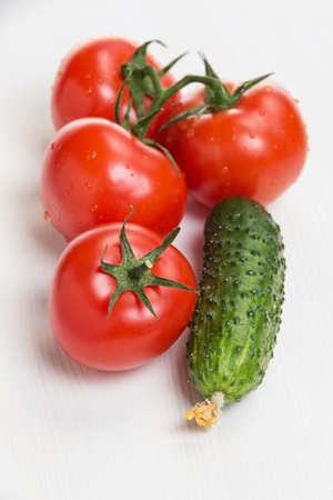 tomatoes and cucumber, on white wooden tableの写真素材