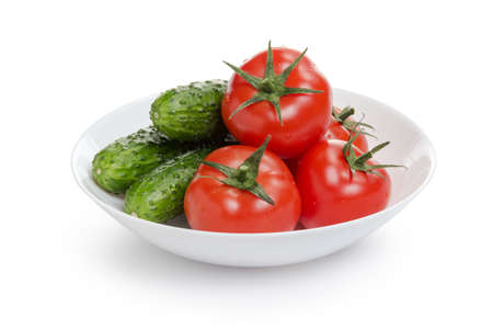 fresh greenhouse cucumbers and tomatoes in bowl, isolated on white backgroundの写真素材