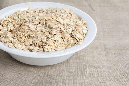 oat flakes in bowl, on burlap surface