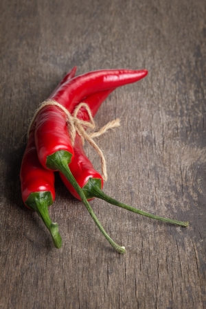 tied red chili peppers on old wooden table, with scratchesの写真素材