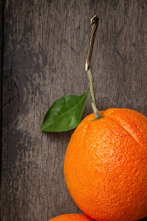 ripe round orange with stem and leaf on wooden table, selective focusの写真素材