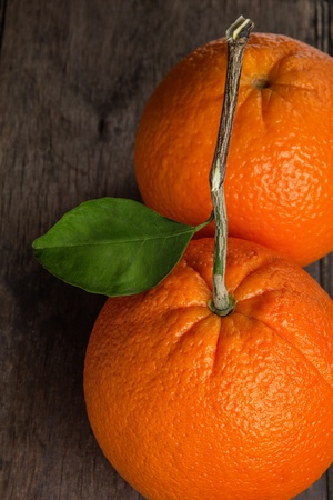 ripe round orange with stem and leaf on wooden table, selective focusの写真素材